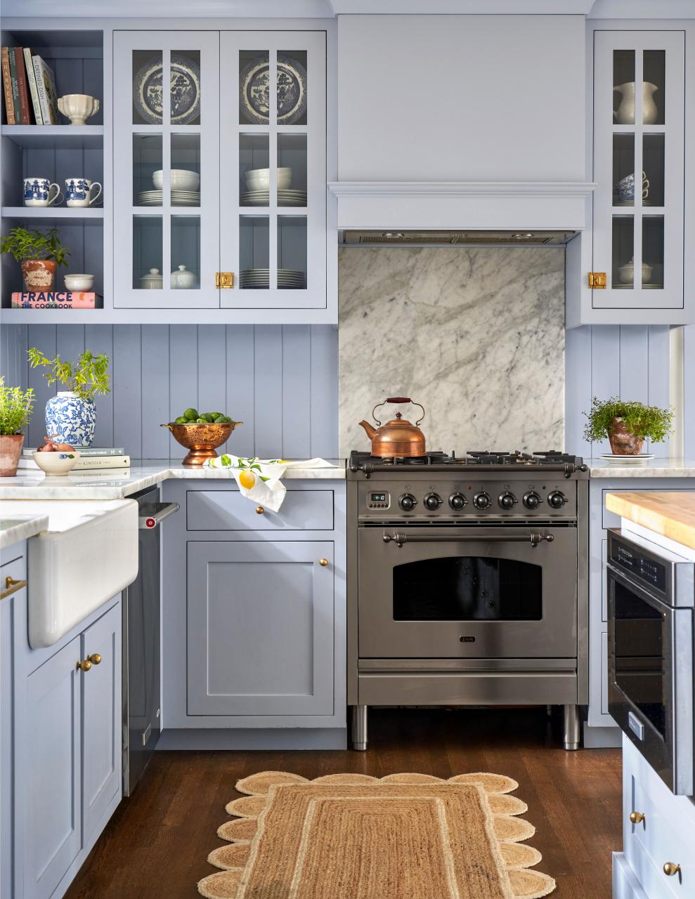 cottage style kitchen with light blue cabinets, butcher block island, carrera marble countertops and paneled backsplash