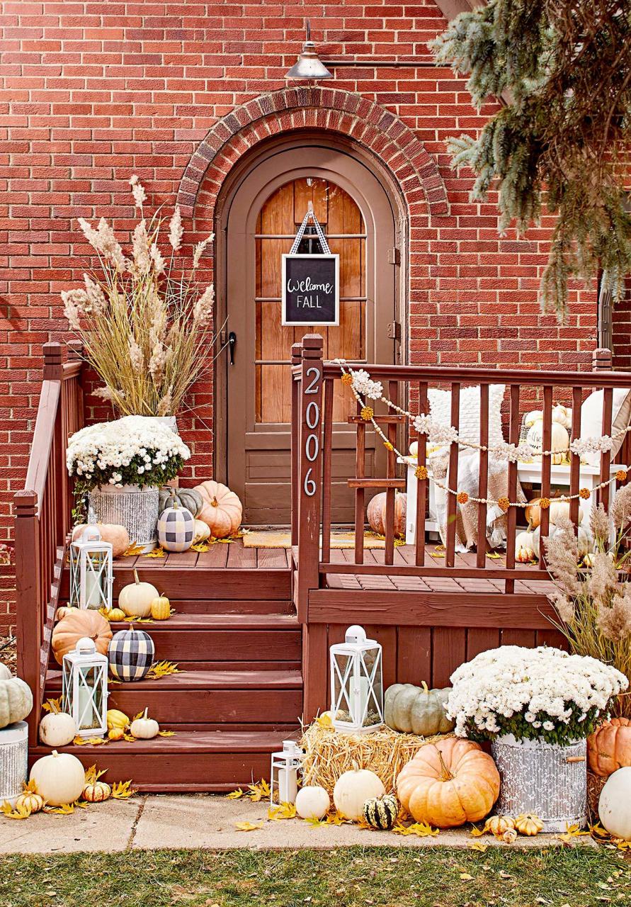 Red front porch with variety of plants and pumpkins