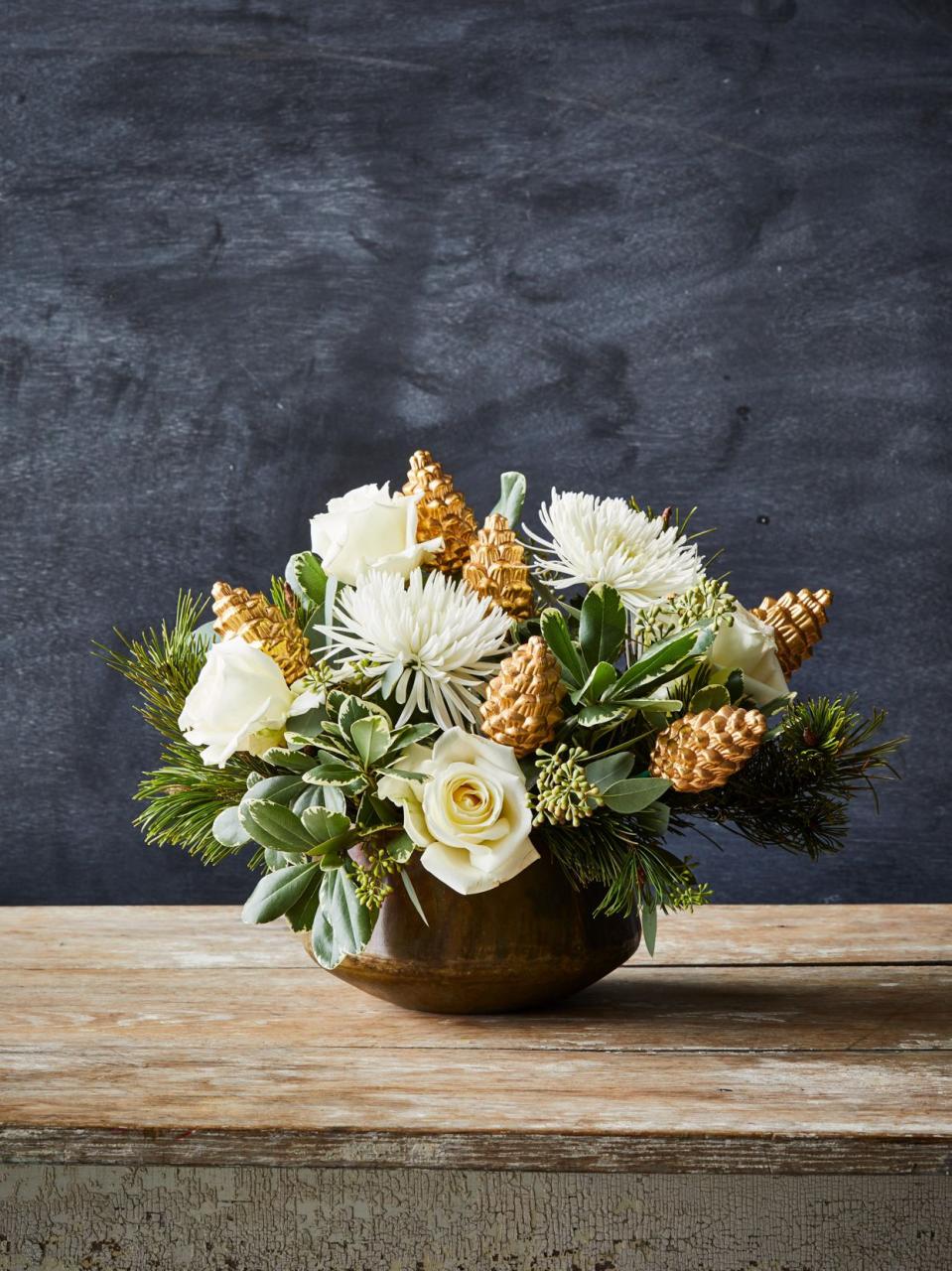 round vase of white flowers and gold pinecones