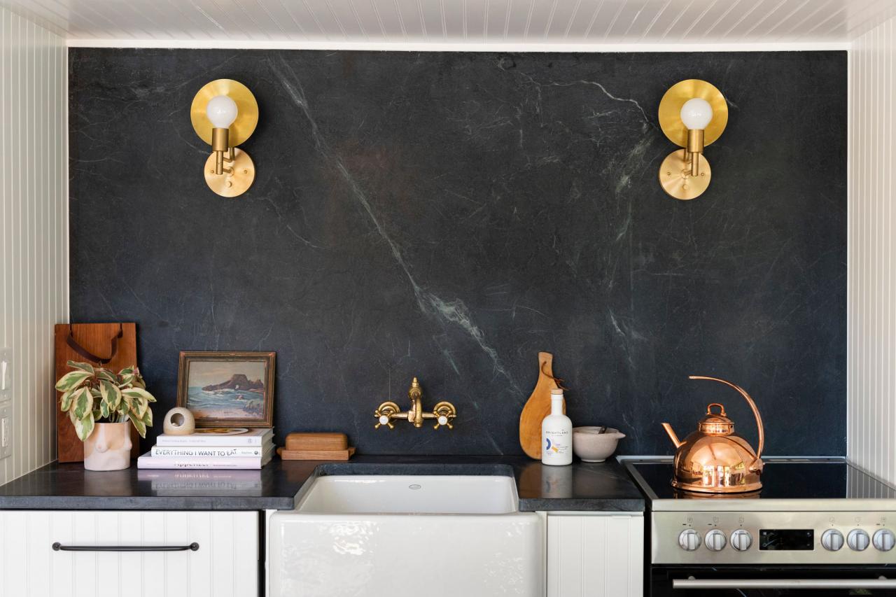 black soapstone back splash and brass sconce and faucet
