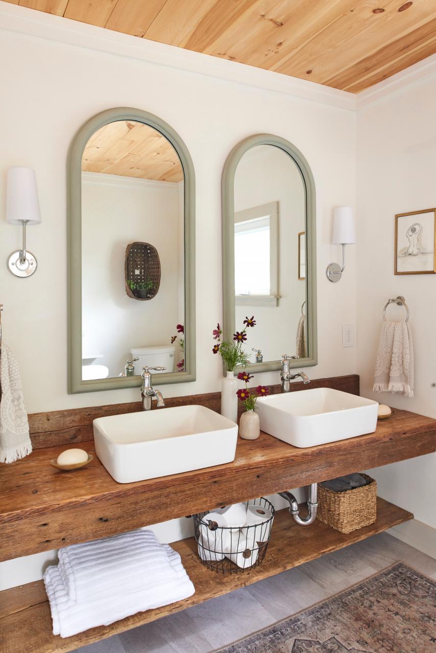 a bathroom with wood countertops and ceiling and two arched mirrors