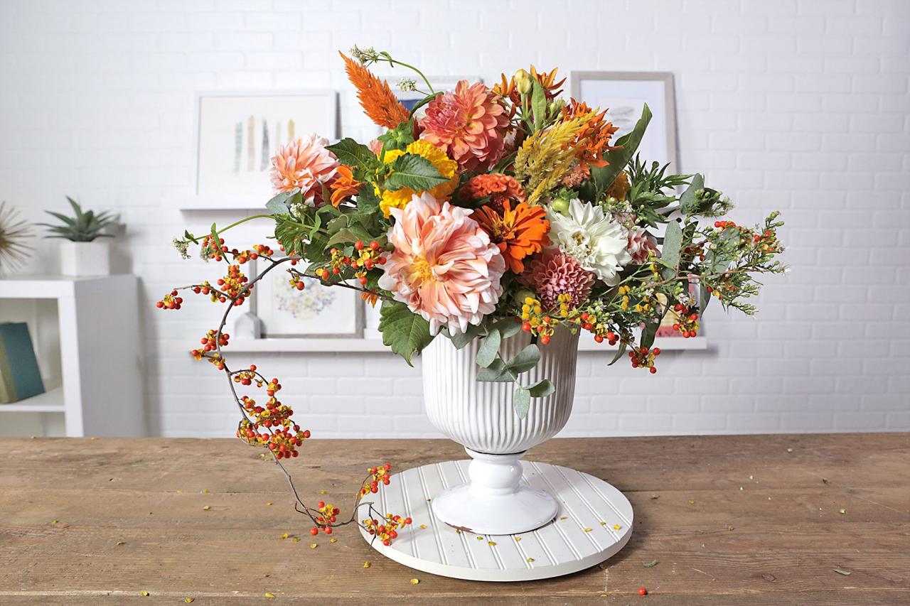 orange flower arrangement in white vase on table
